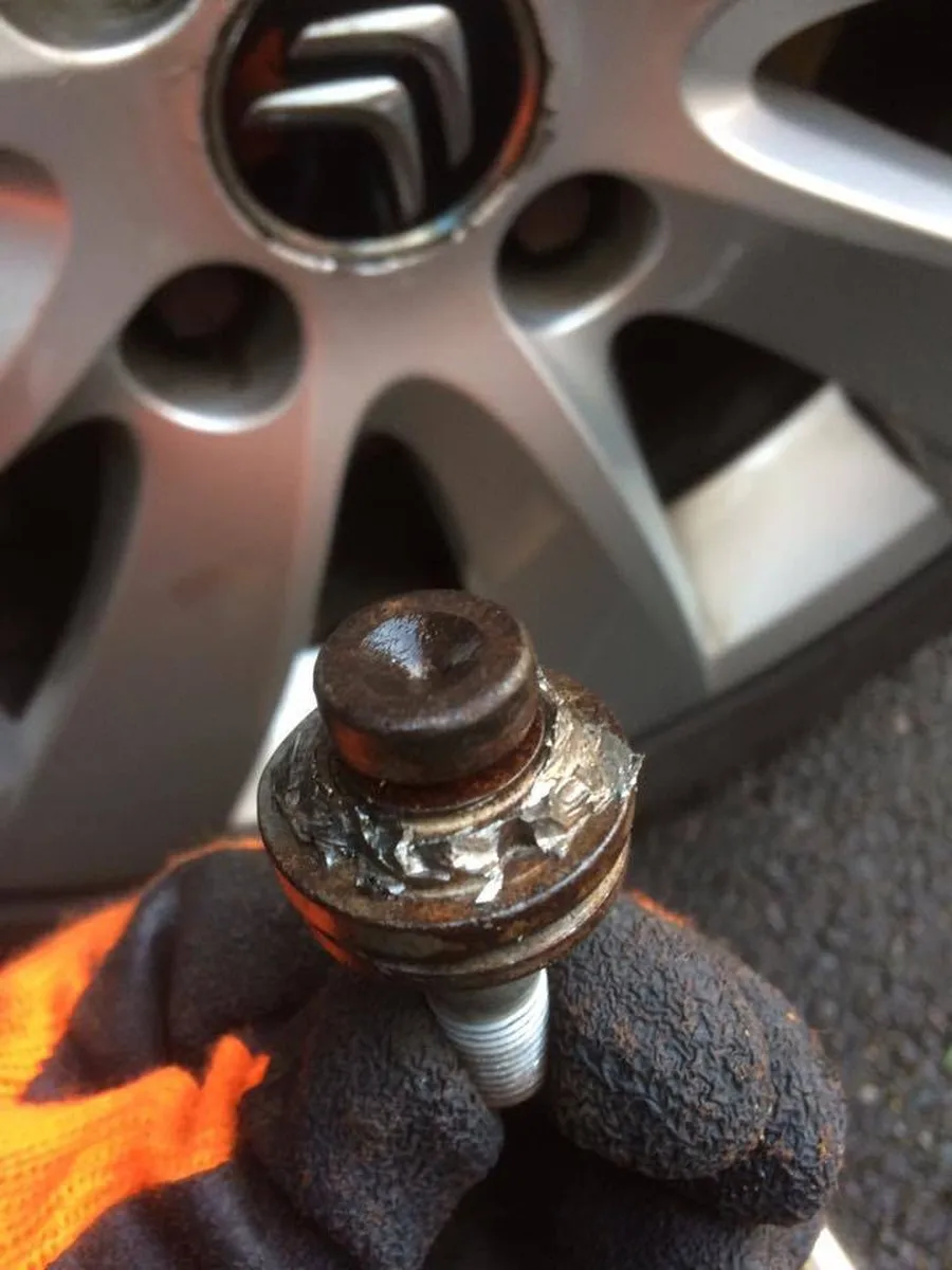 A corroded locking wheel nut being removed from a vehicle wheel
